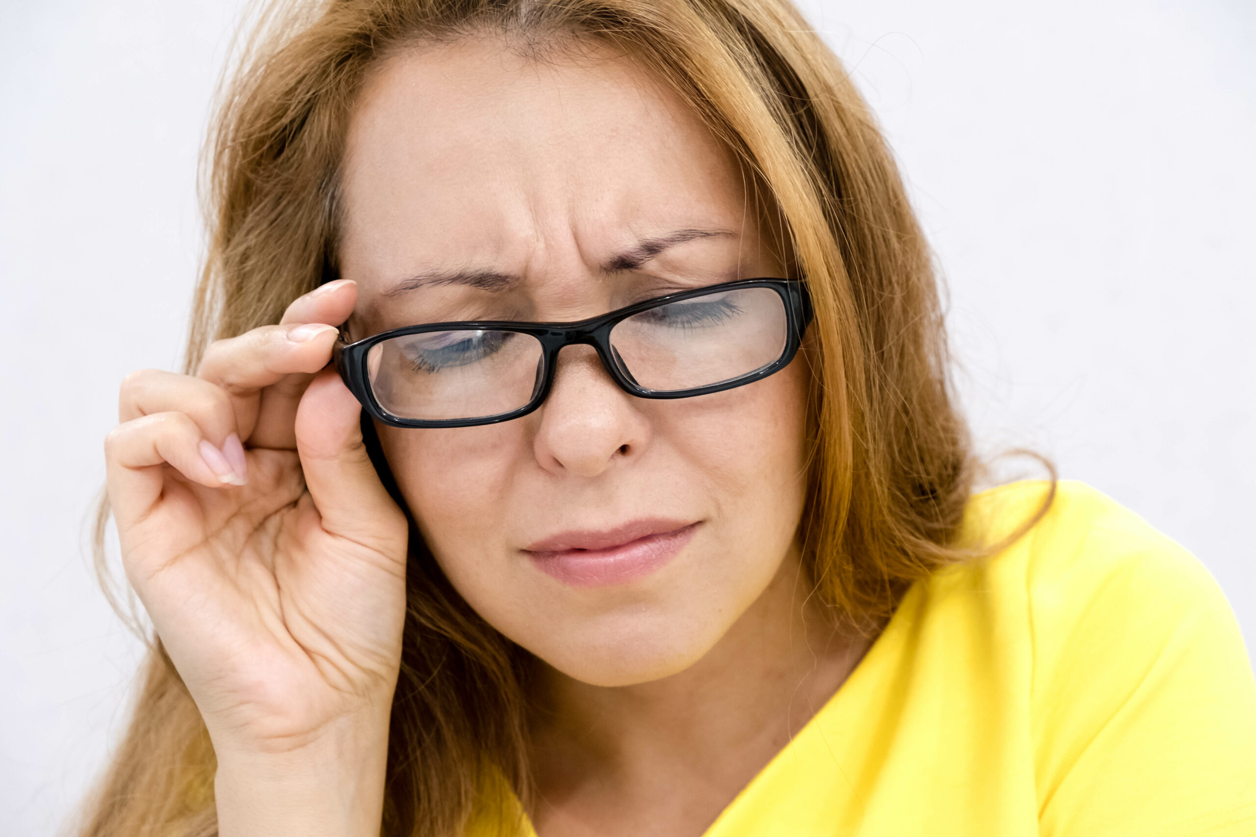 Closeup portrait, mature woman with black eye glasses trying to read book, having difficulties seeing text because vision problems. look down, trying to share the information below
